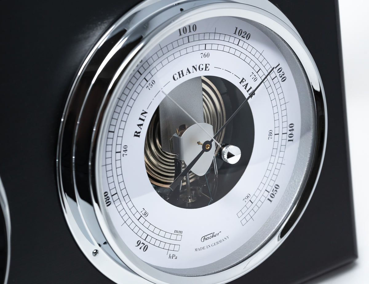 Close-up of an analog German barometer with chrome trim and weather readings display.