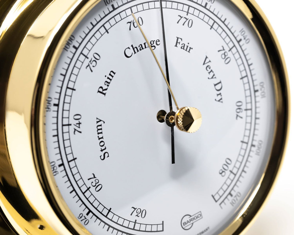 Close-up of a German brass barometer showing weather conditions and pressure scale.