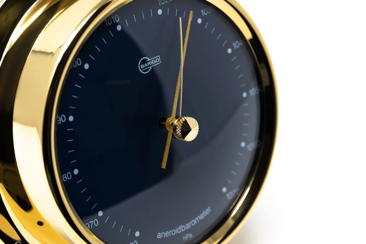 Gold aneroid barometer with black dial and precision weather measurement display