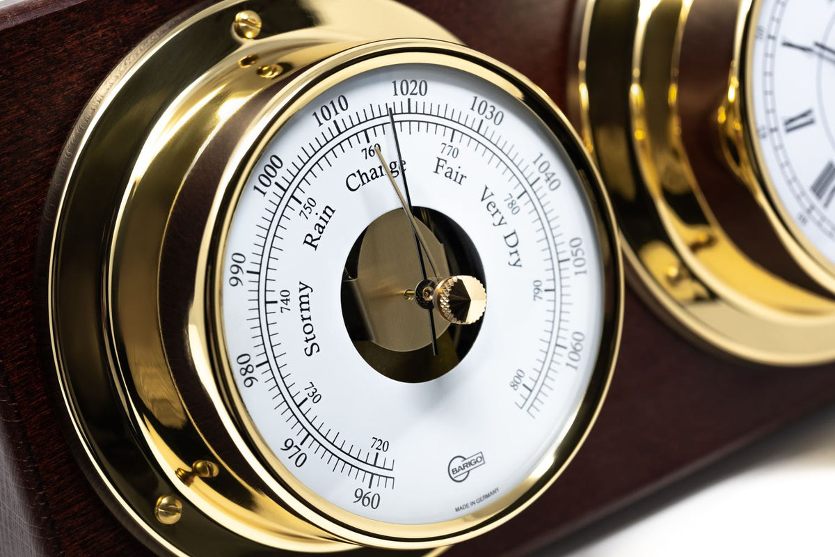Close-up of classic German barometer with gold frame and wood mount, weather dial visible.
