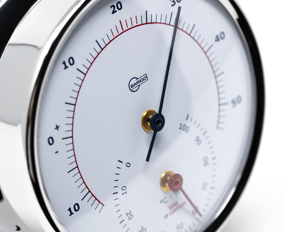 Close-up of a German-made analog barometer and hygrometer with white dial and chrome case