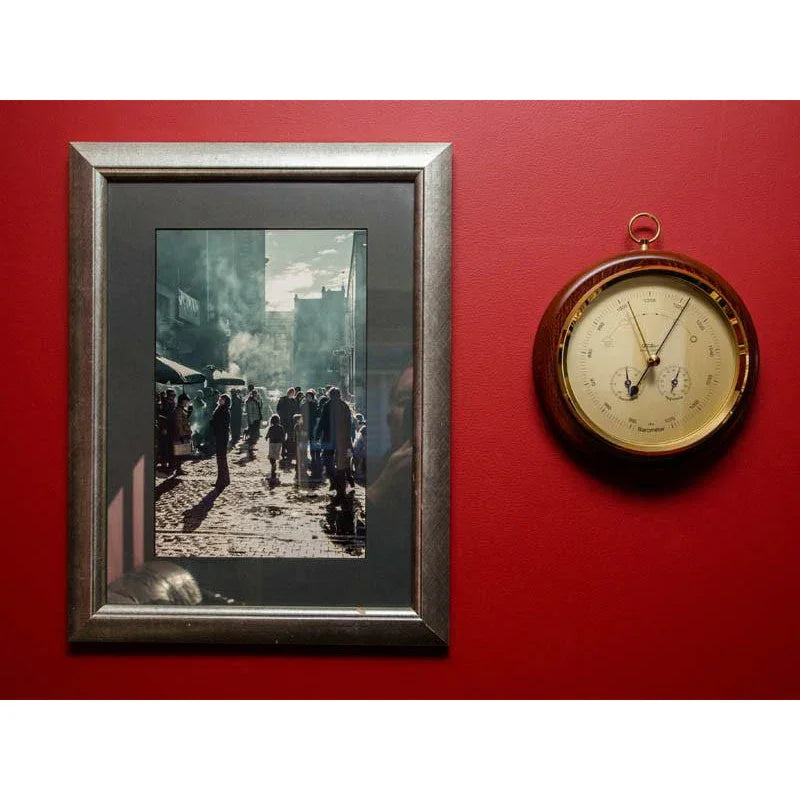 Classic round barometer and framed photo on red wall, home weather station decor