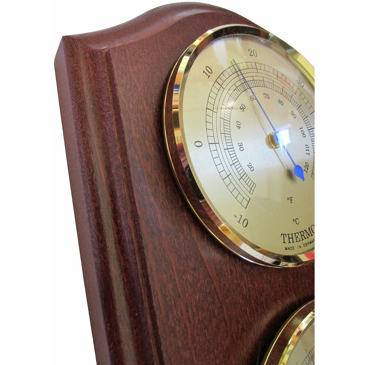 Classic analog weather station with thermometer on polished wood panel