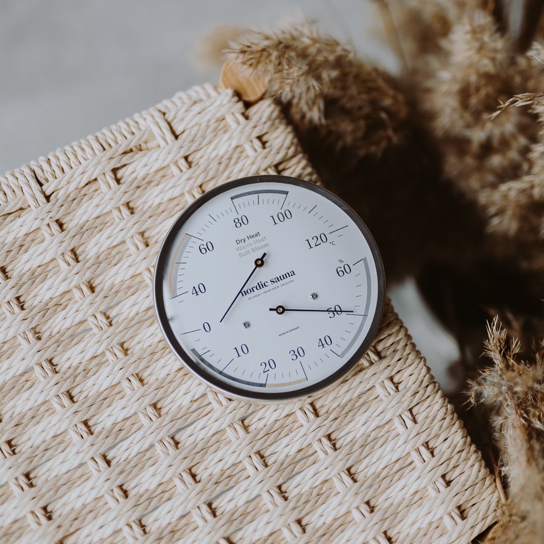 Round sauna thermometer and hygrometer on woven surface, measures temperature and humidity