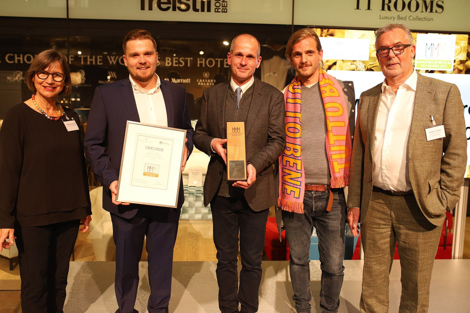 Group of people at an awards ceremony holding a certificate and trophy, indoor event setting