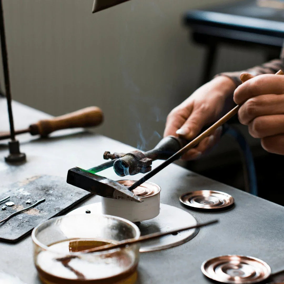 Craftsman hand-assembling German barometer or clock parts with tools on a workbench